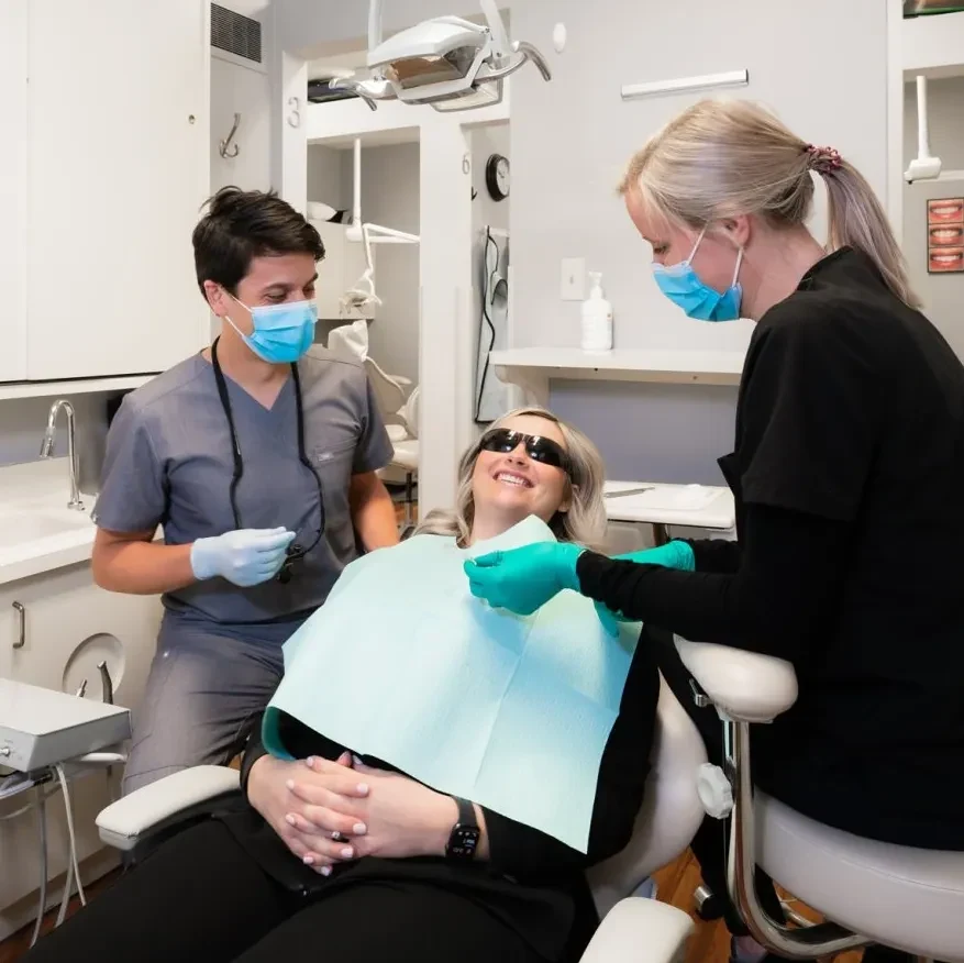 A patient smiling with two members of the Ross Dental care team